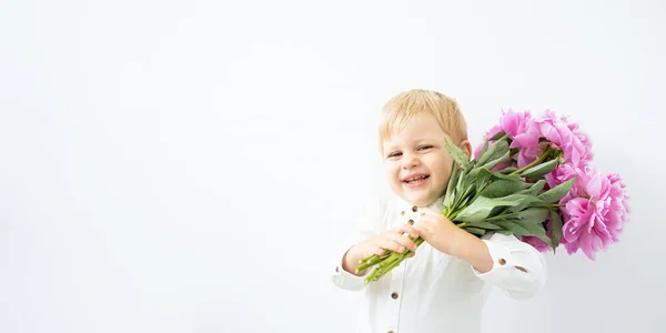 Bannière. petit garçon blond avec un gros bouquet de pivoines roses sur fond blanc. Amour et concept romantique — Photo