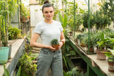 Serada kil çömlekte çiçek tutan gündelik giysiler içindeki genç ve çekici kadınlar..