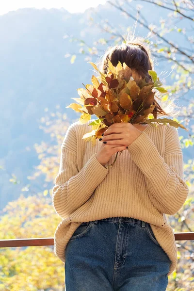 Atractiva mujer de mediana edad feliz en suéter sostiene ramo de hojas coloridas, cubre su cara —  Fotos de Stock