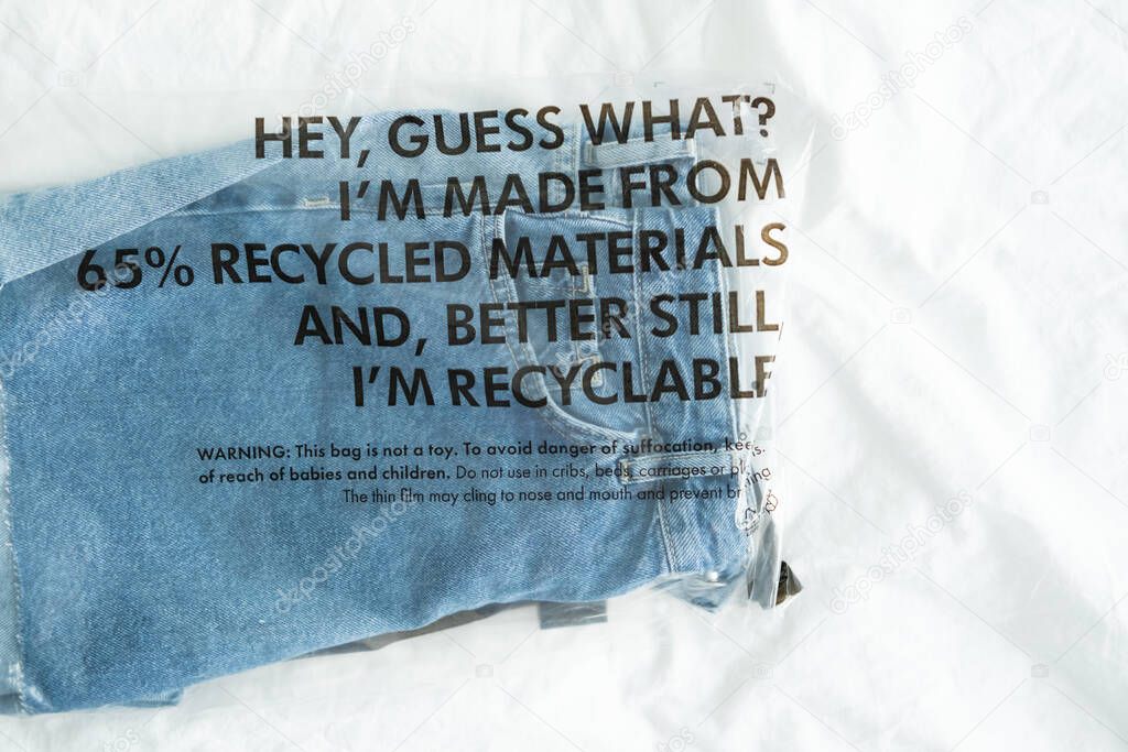 blue jeans in plastic bag with tag recycled materials and recyclable. zero waste concept
