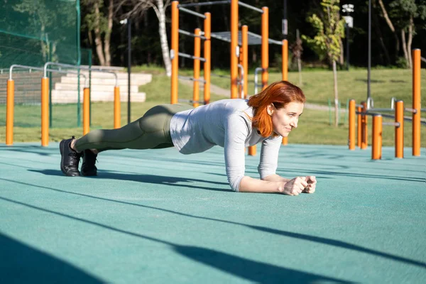 Atletický zázvor žena pracuje venku na městském sportovišti v slunečný podzimní den — Stock fotografie