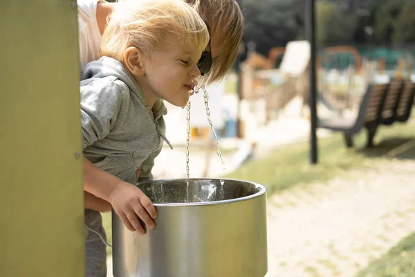 Ojciec Pomaga Synowi Pić Wodę Publicznej Fontanny Parku — Zdjęcie stockowe