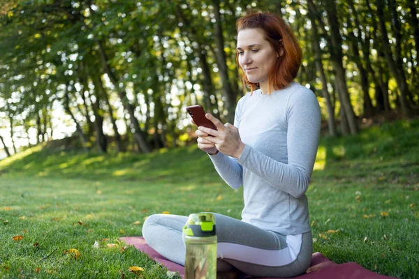 Atletická Zázvorová Žena Sportovním Oblečení Používající Mobilní Telefon Parku Zdraví — Stock fotografie