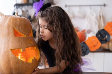 Cadılar Bayramı 'nı kutlamak için evde balkabağıyla cadı kostümü giymiş tatlı bir kız..