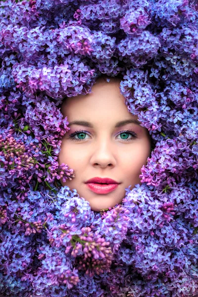 Schönes Mädchen in fliederfarbenen Blumen. — Stockfoto