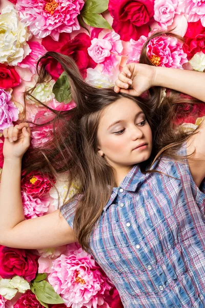 Молода красива дівчина лежить на квітах . — стокове фото