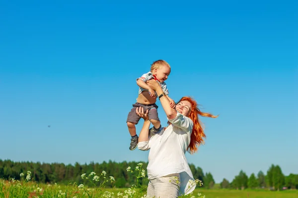 Güzel kızıl saçlı anne bebeğini alanında ile oynarken. — Stok fotoğraf