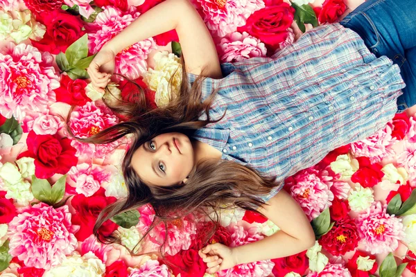 Jovem menina bonita encontra-se nas flores . — Fotografia de Stock