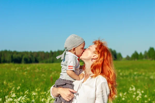 Hermosa madre pelirroja jugando con su bebé en el campo . —  Fotos de Stock
