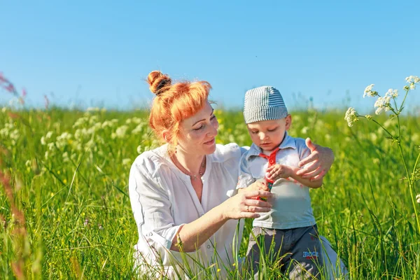 Belle mère rousse jouant avec son bébé dans le champ . — Photo