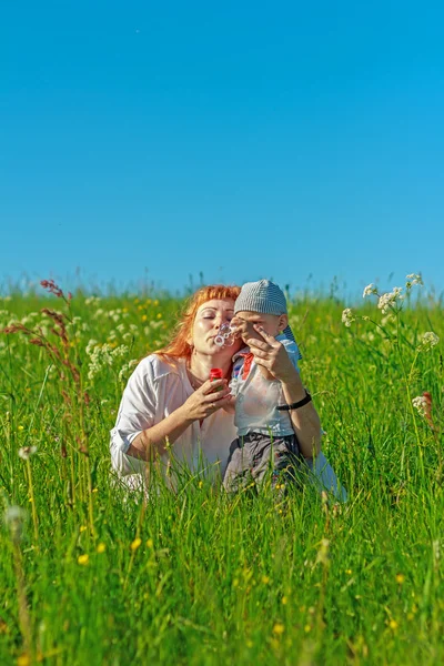 Красивая рыжая мать играет со своим ребенком в поле . — стоковое фото