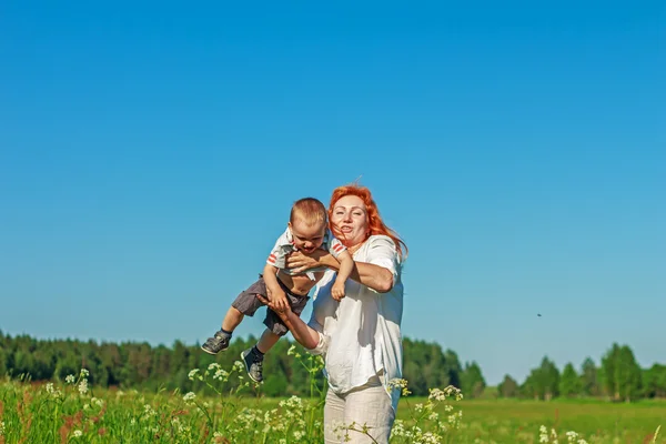 Güzel kızıl saçlı anne bebeğini alanında ile oynarken. — Stok fotoğraf