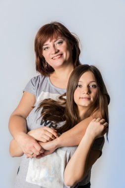 Anne ve kızı ayakta ve kameraya bakıyor.