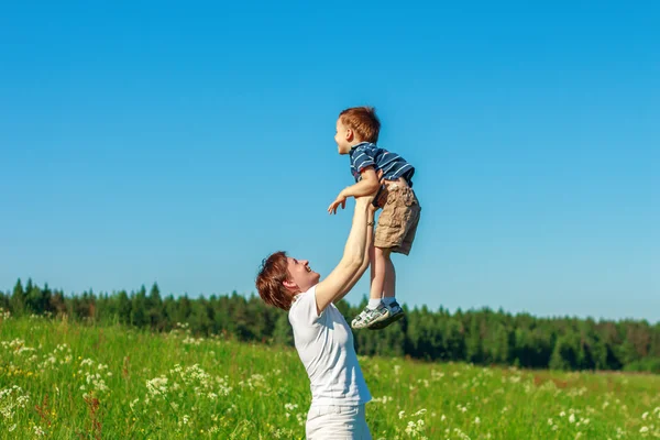 Mladá brunetka s krátkými vlasy, hrát si s jeho synem v poli — Stock fotografie