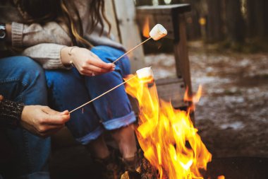 Sevgi dolu bir çift ateşin yanında şekerleme hazırlar. Sonbahar ormanı, romantik bir gün. Seçici odak