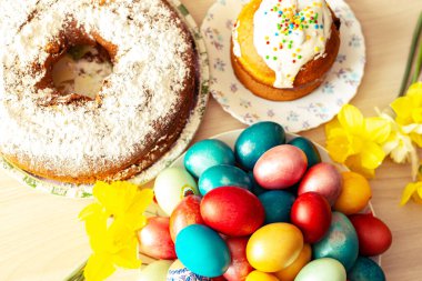 Paskalya ortodoks tatlı ekmeği, kulich, renkli yumurta ve bir buket nergis. Parlak güneş ışığı. Geleneksel Paskalya kahvaltısı. 