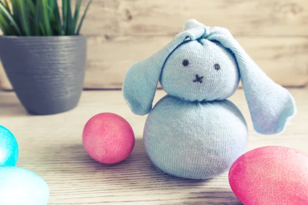 Oyuncak Paskalya tavşanı ve tahta arka planda yumurtalar. Paskalya süslemeleri, bayram sembolleri. 