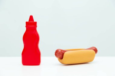 Hafif arka planda bir şişe ketçap ve sosisli sandviç. Klasik sokak atıştırmalığı. Sağlıksız yiyecekler. 