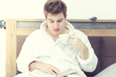 Kafkasyalı genç bir adam elinde bir fincan kahveyle kitap okuyor. Sabahın erken saatlerinde.