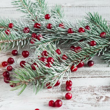 Ahşap bir masa üzerinde kızılcık ve Noel ağacı dalları