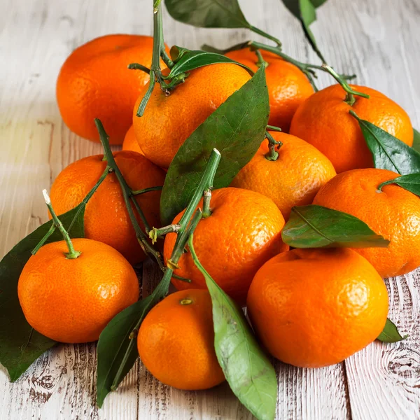 Tangeriner med löv på ett träbord — Stockfoto