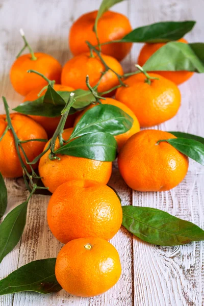 Tangerines met bladeren op een houten tafel — Stockfoto