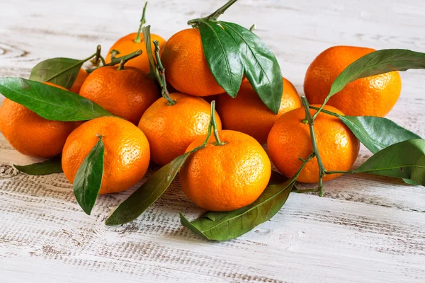 Tangerines with leaves on a wooden table — Stock Photo, Image