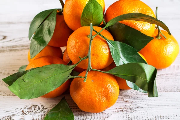 Tangeriner med löv på ett träbord — Stockfoto