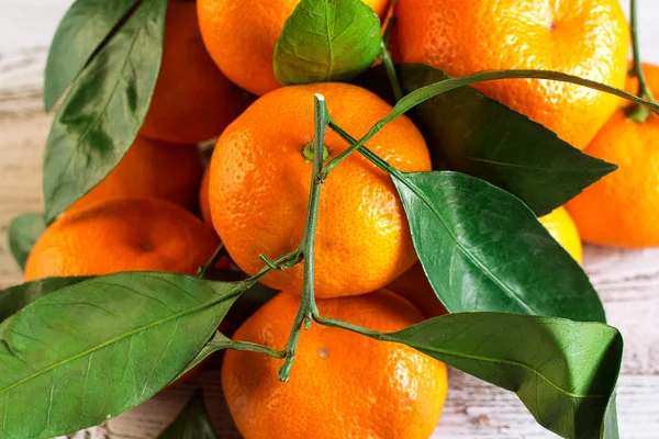 Tangeriner med löv på ett träbord — Stockfoto