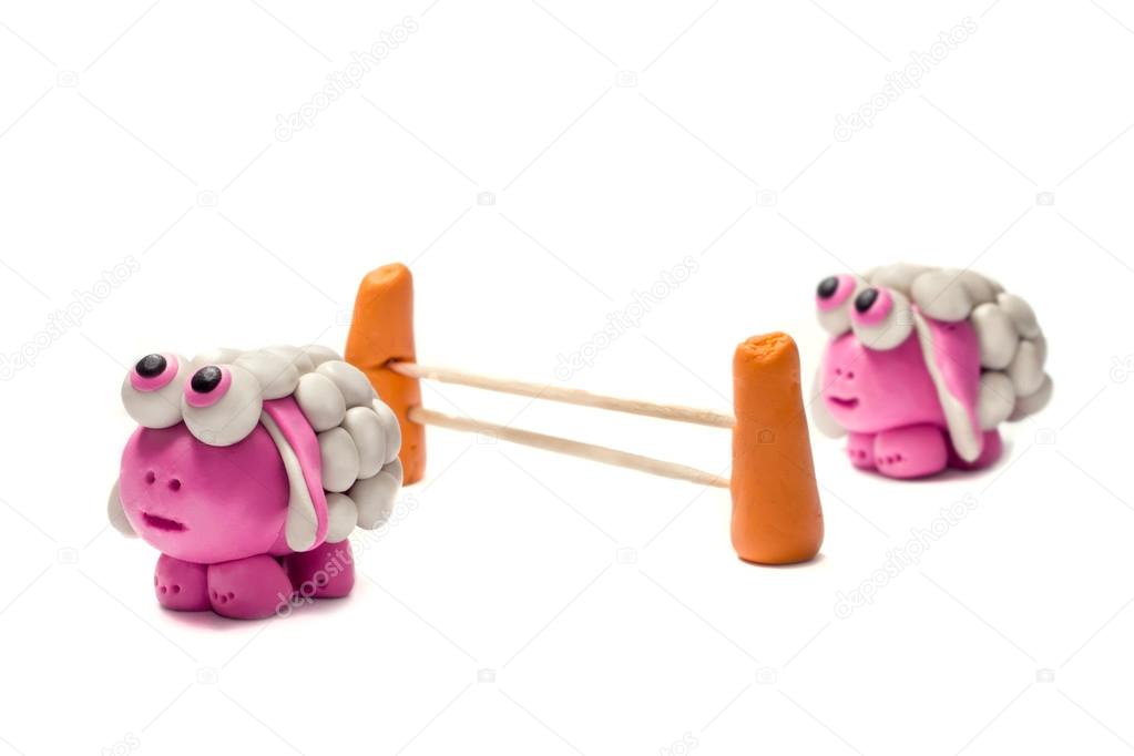 Little plasticine sheep jumping over a fence.