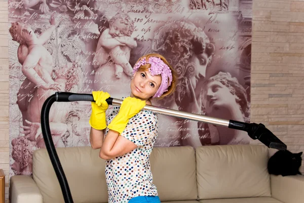 Huisvrouw met stofzuiger in de woonkamer — Stockfoto