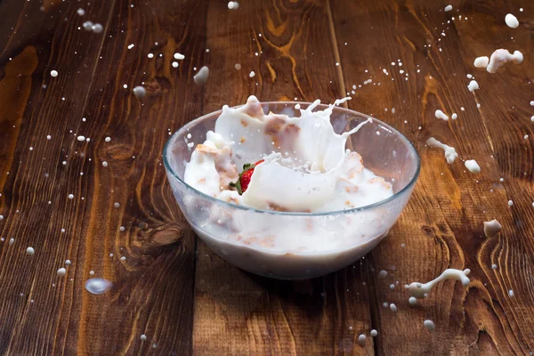 Morango caindo em uma tigela com leite e cereais . — Fotografia de Stock