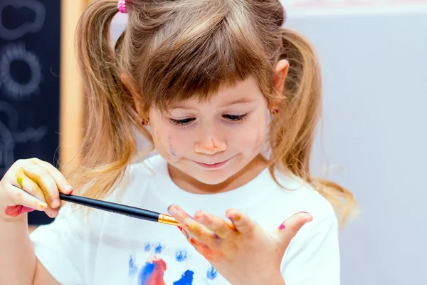 Küçük güzel kız boyalar çizer.