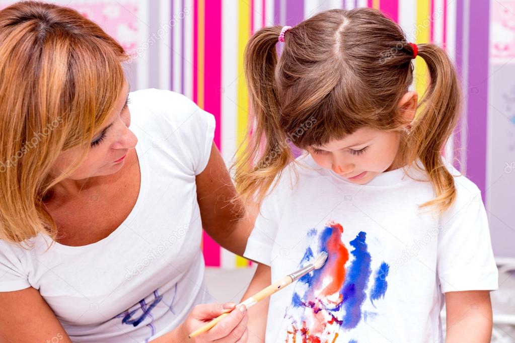 Mom draws paints on a T-shirt daughter.