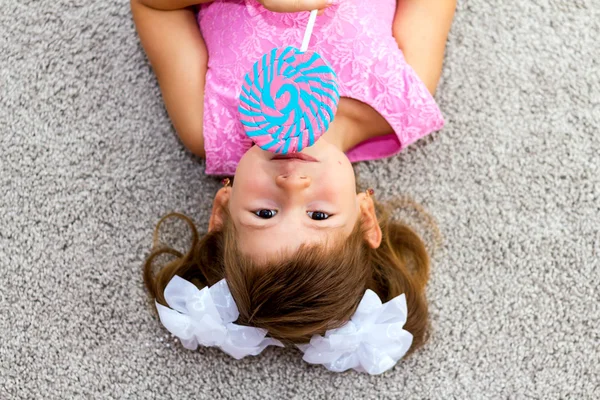 Küçük kız yerde yatıyor. Kameraya bakarak.