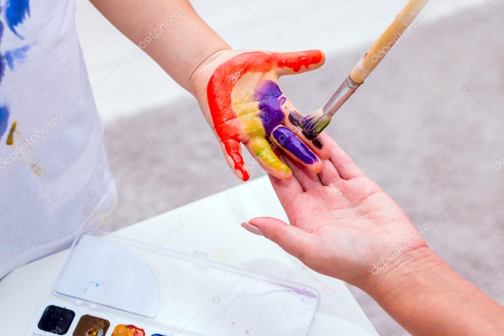 Hands of a child painted with bright colors.