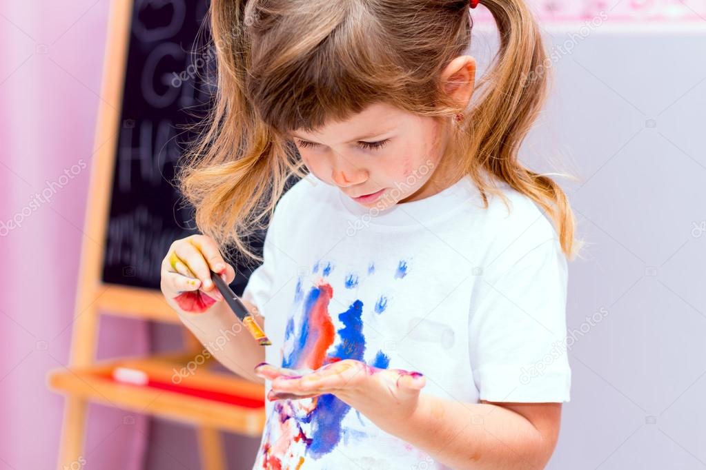 Little beautiful girl draws paints.