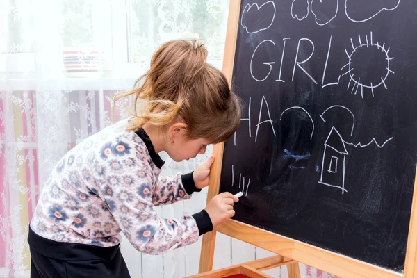 Маленькая красивая девочка рисует на доске . — стоковое фото