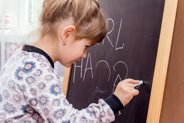 Lilla vackra flicka ritning på en svart tavla. — Stockfoto