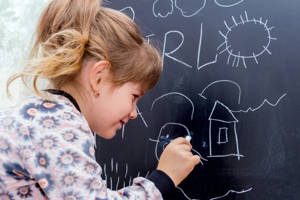 Lilla vackra flicka ritning på en svart tavla. — Stockfoto