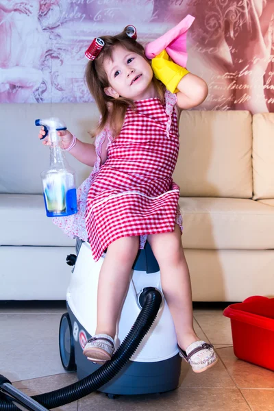 Kleines Mädchen sitzt auf dem Staubsauger. — Stockfoto