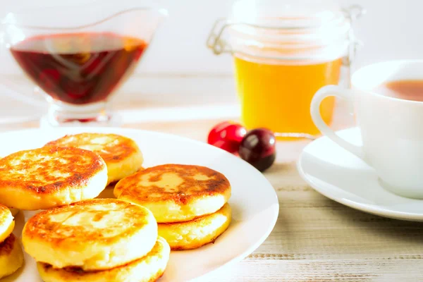 Delicious cottage cheese pancakes with cherry jam and honey. — Stock Photo, Image