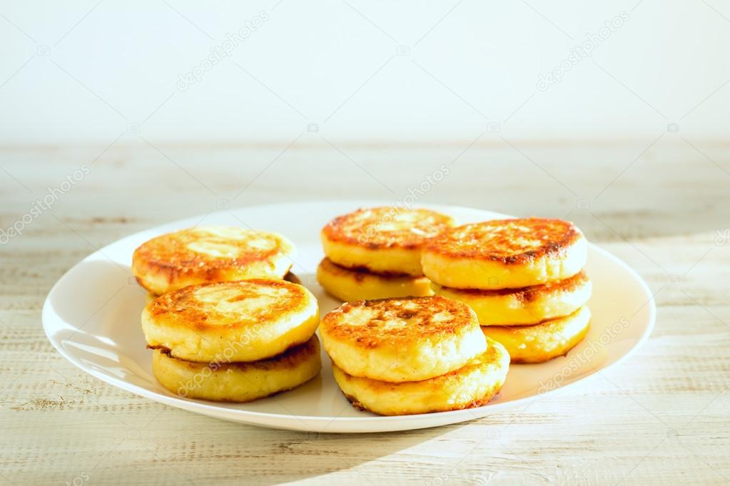 Delicious cottage cheese pancakes on a wooden background.
