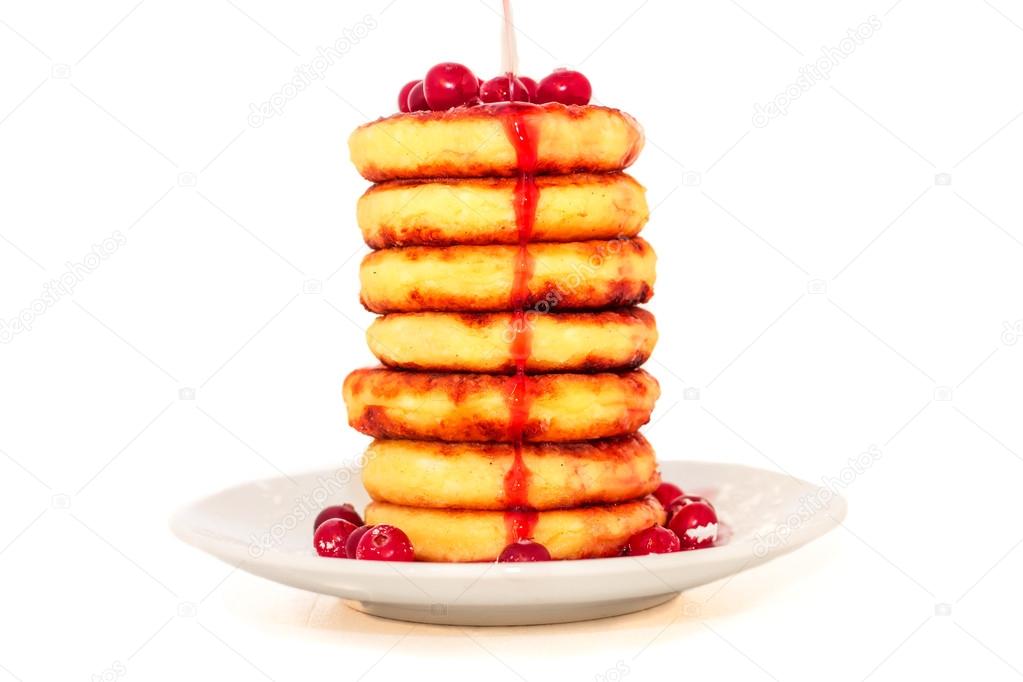 Cottage cheese pancakes with cherry jam and cranberries on a pla