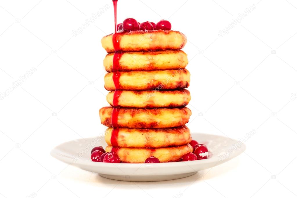 Cottage cheese pancakes with cherry jam and cranberries on a pla