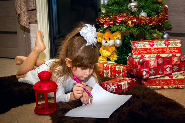 Mooi meisje schrijft een brief aan de Kerstman. — Stockfoto