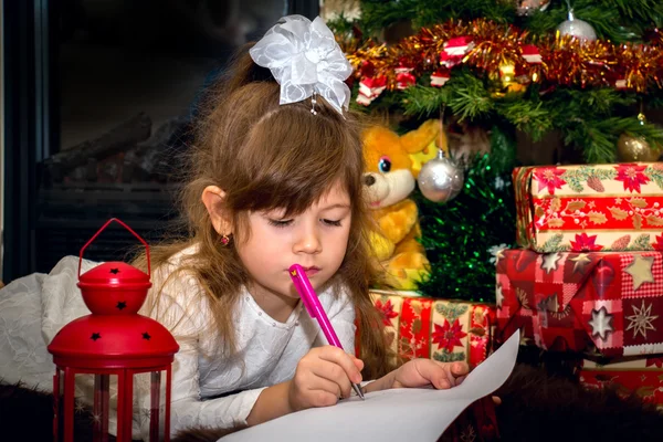 Pequena menina bonita escreve uma carta para Santa . — Fotografia de Stock