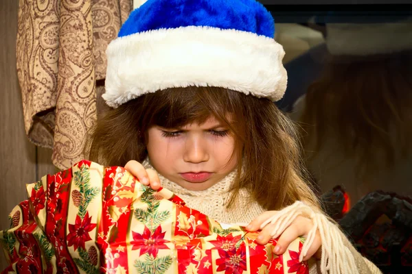 Pequena menina ofendida desembrulha um presente . — Fotografia de Stock