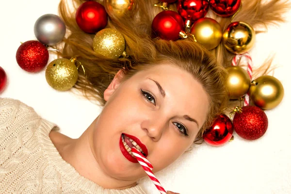 Hermosa rubia con un caramelo de Navidad acostada en un fondo blanco — Foto de Stock
