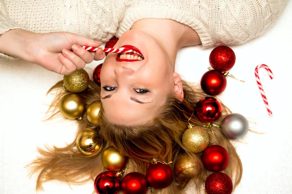 Hermosa rubia con un caramelo de Navidad acostada en un fondo blanco — Foto de Stock